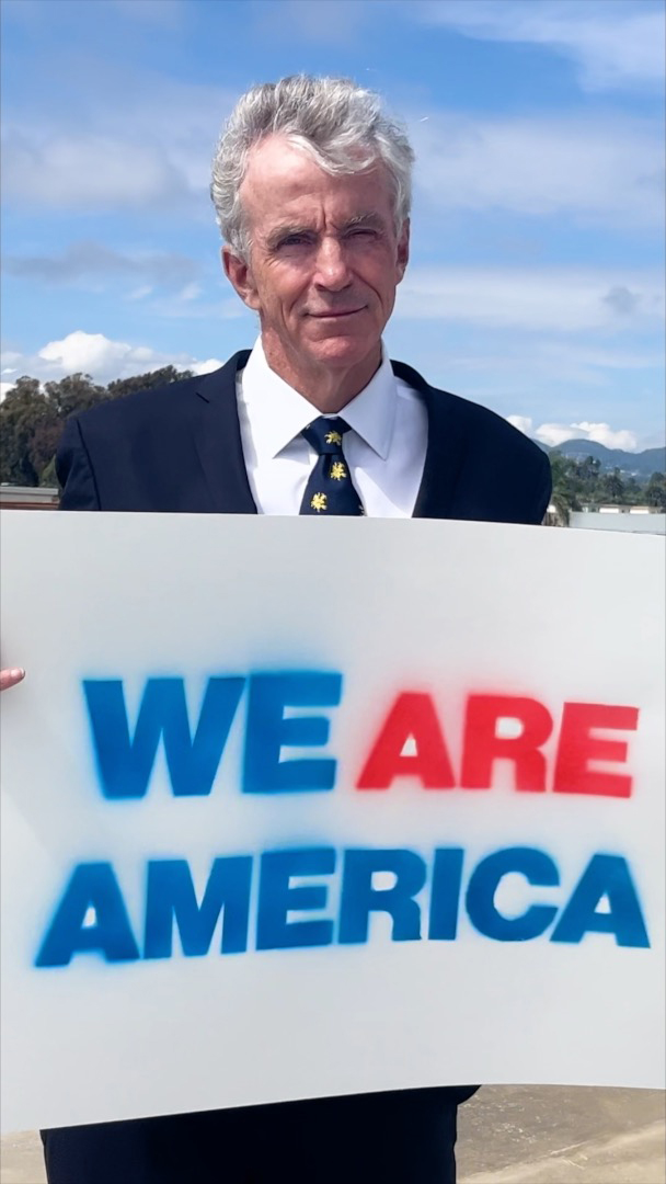 Dan Greaney holding a 'We Are America' sign